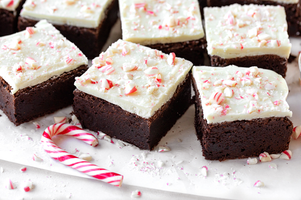 A few freshly cut Peppermint Bark Brownies next to a candy cane | thecozyapron.com