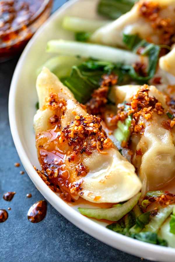 Closeup of Chili Crisp drizzled over Potstickers and bok choy | thecozyapron.com