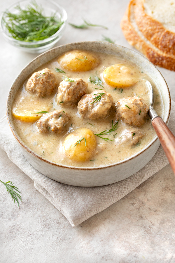 A comforting bowl of Swedish Meatball Soup with a couple slices of bread | thecozyapron.com