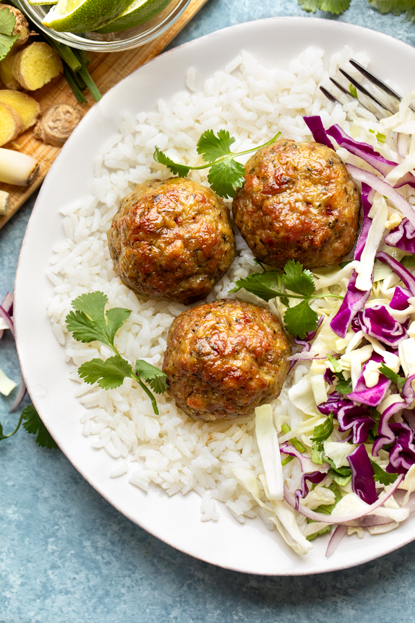 A closeup view of Pork Meatballs with Ginger and Lemongrass, on a bed of rice with Chili-lime slaw | thecozyapron.com