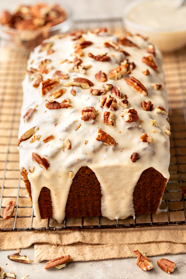 A freshly baked loaf of Buttered Pecan Banana Bread with brown butter icing and toasted pecans on top | thecozyapron.com