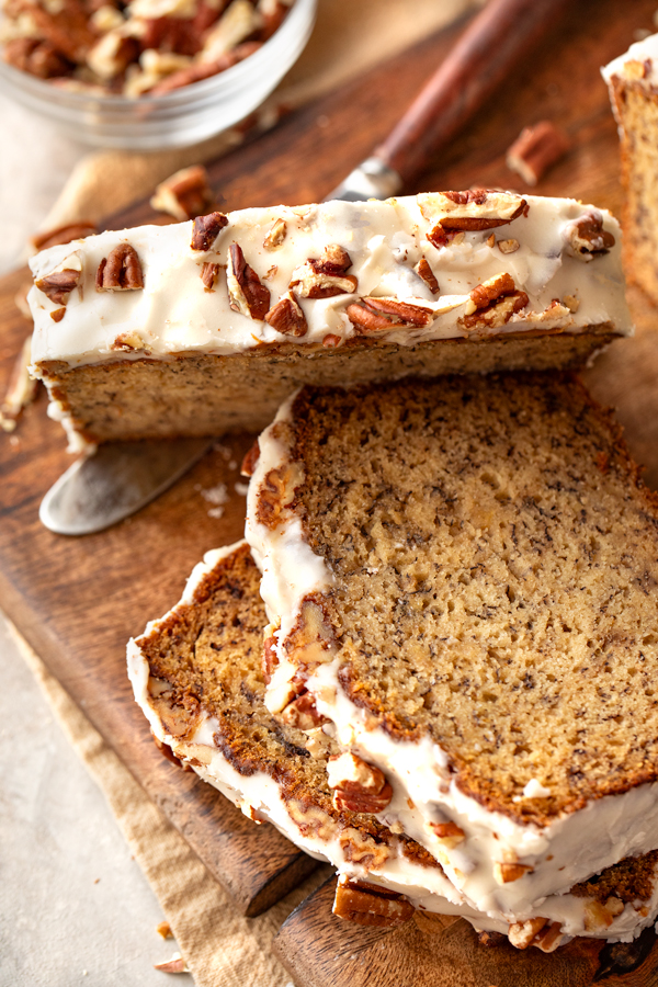 Close-up and overhead view of freshly baked buttered pecan banana bread with icing and toasted pecans | thecozyapron.com