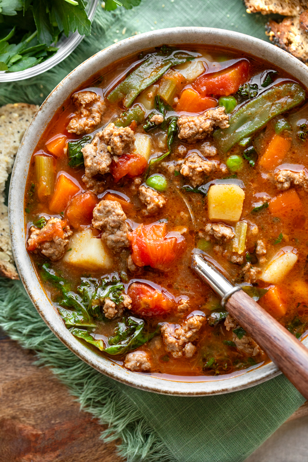 Overhead shot of a big bowl of Easy Vegetable Beef Soup with a few slices of bread | thecozyapron.com