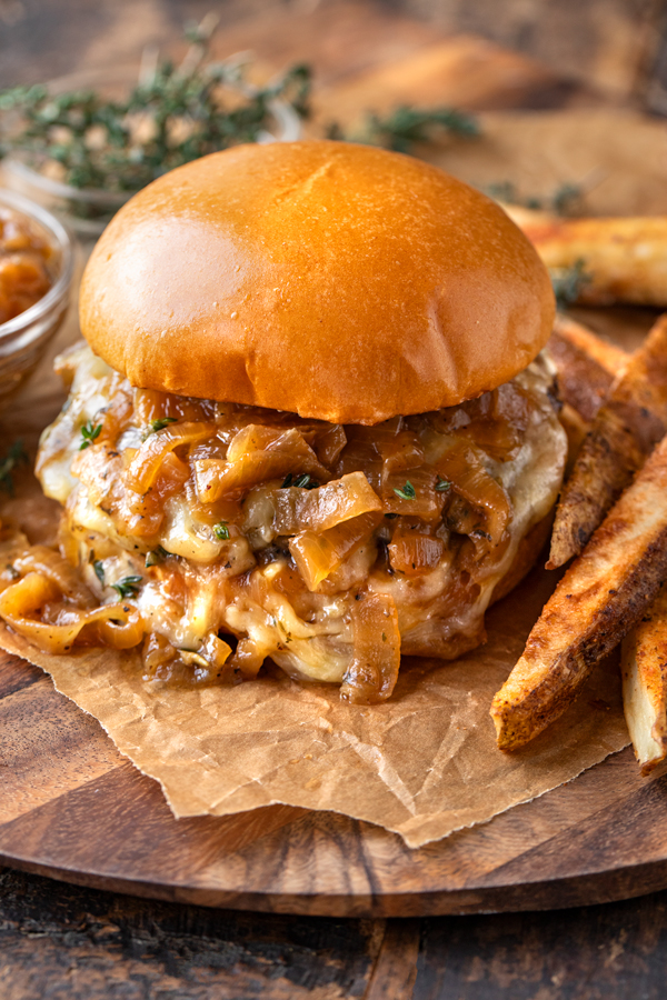 Close-up on a French Onion Burger showing the melted cheese and caramelized onion sauce! | thecozyapron.com