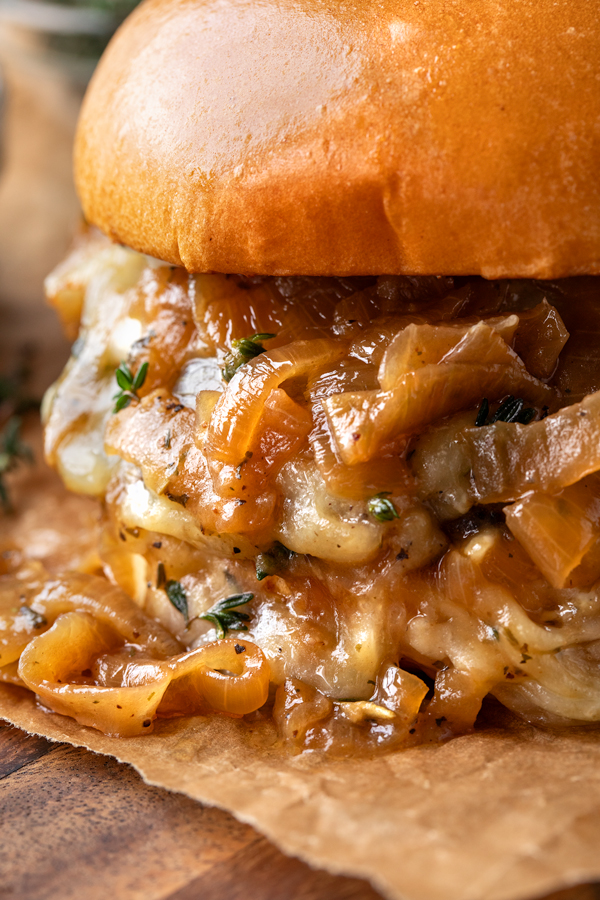 Super close-up on a French Onion Burger showing the melted cheese and caramelized onion sauce! | thecozyapron.com