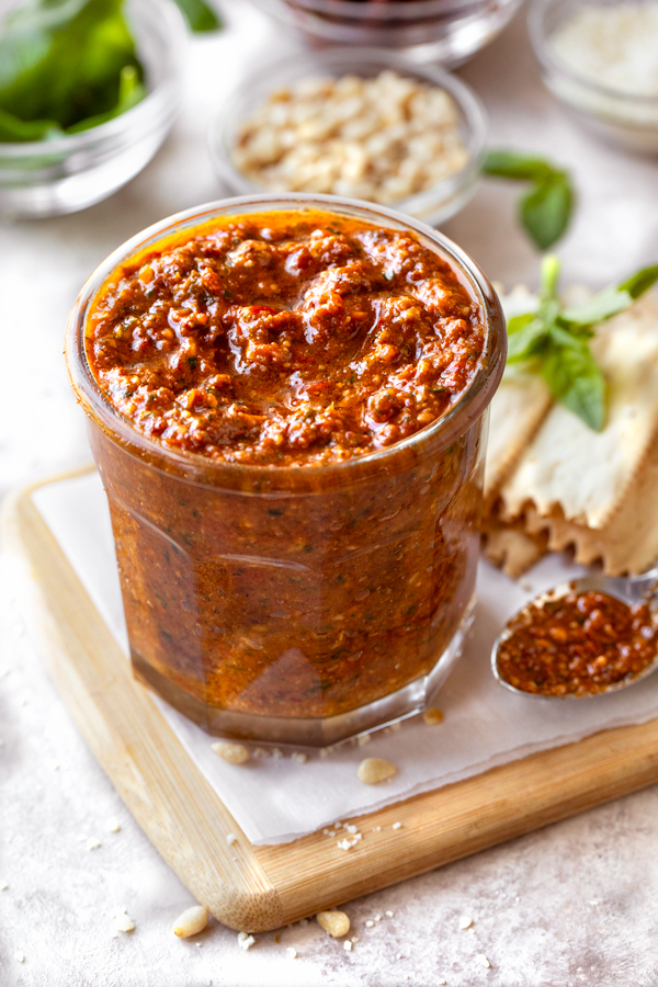 A serving glass of Sun Dried Tomato Pesto with crackers on the side | thecozyapron.com