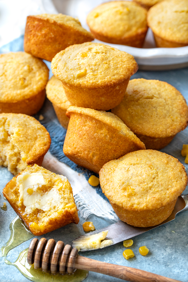 A stack of Cornbread Muffins with a honey dipper full of honey on the side | thecozyapron.com