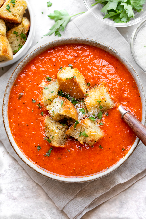 Overhead shot of a bowl of Roasted Red Pepper and Tomato Soup topped with crispy croutons | thecozyapron.com