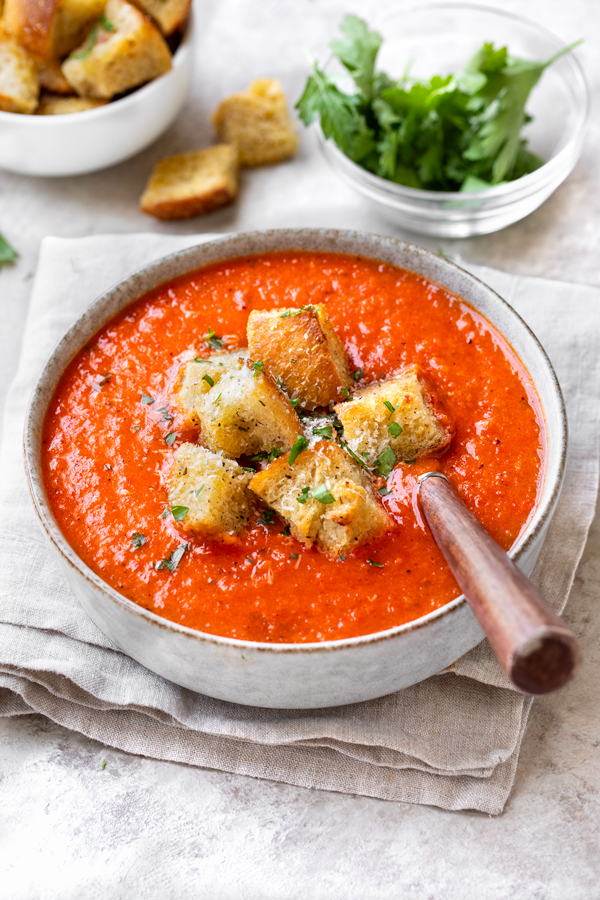 A bowl of Roasted Red Pepper and Tomato Soup, topped with crispy croutons | thecozyapron.com