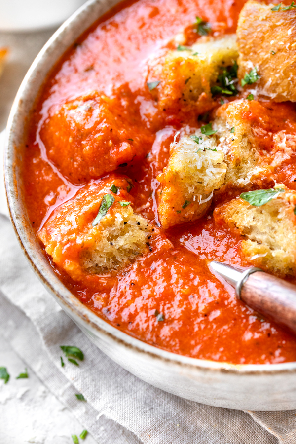 Closeup on a bowl of Roasted Red Pepper and Tomato Soup, topped with crispy croutons | thecozyapron.com