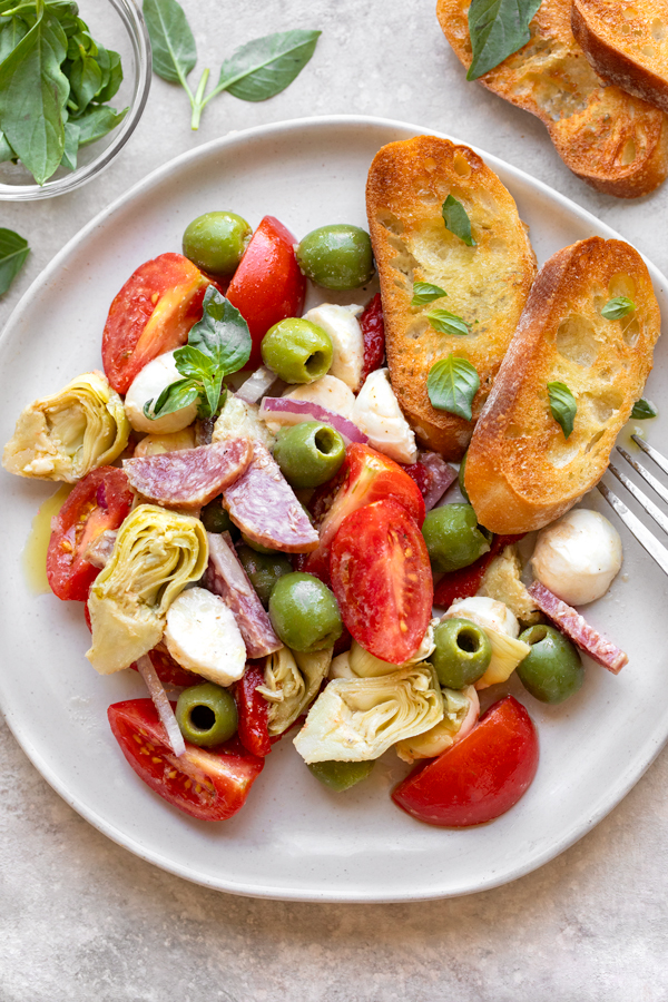 An overhead view of a serving of Antipasto Salad with Garlic Crostini on the side | thecozyapron.com