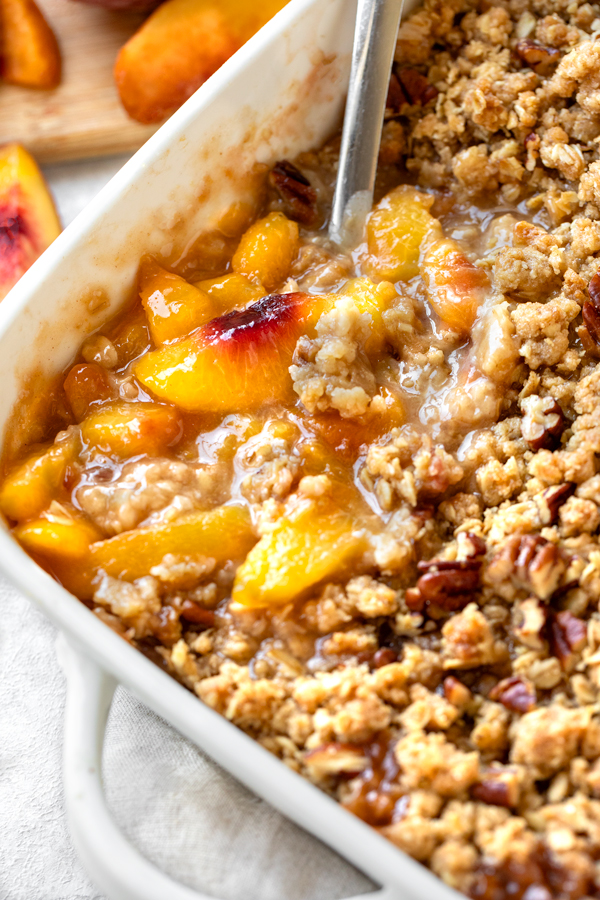 A serving of Peach Crisp spooned from the baking dish | thecozyapron.com