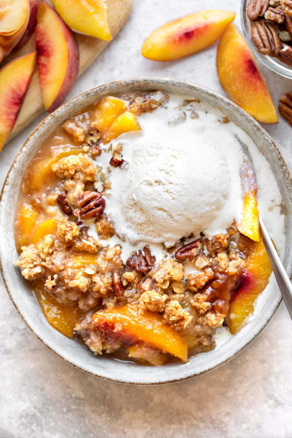A bowl of homemade Peach Crisp with a scoop of vanilla ice cream | thecozyapron.com
