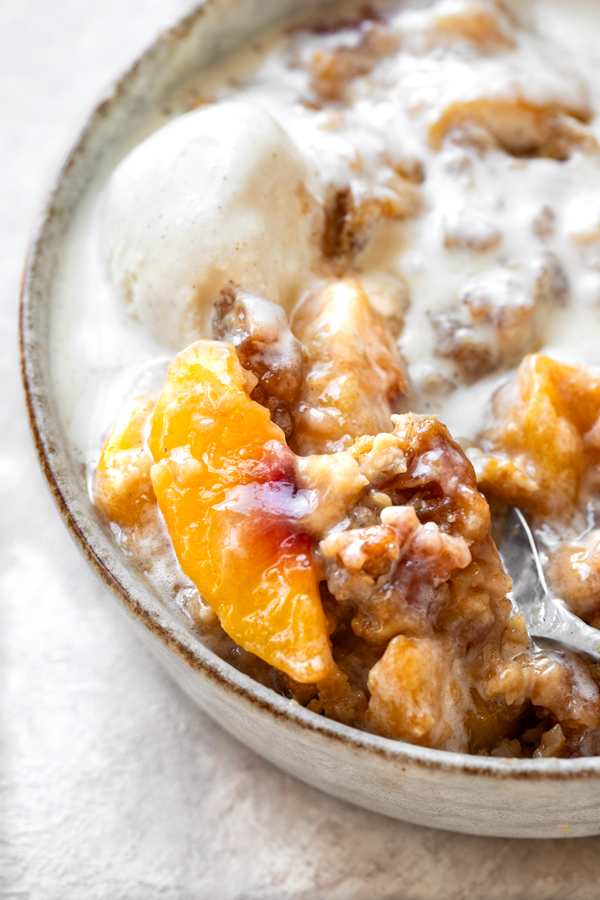 Closeup on a spoonful of Peach Crisp and vanilla Ice Cream| thecozyapron.com