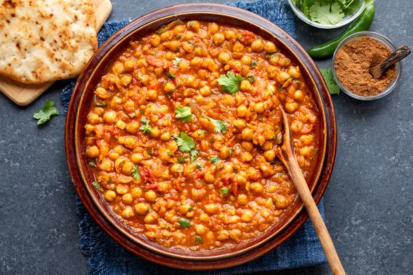 A serving platter full of Chana Masala with garlic naan on the side | thecozyapron.com