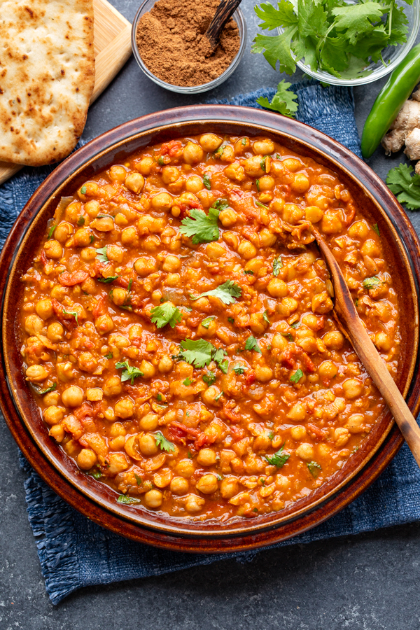 A serving dish full of Chana Masala with garlic naan on the side | thecozyapron.com