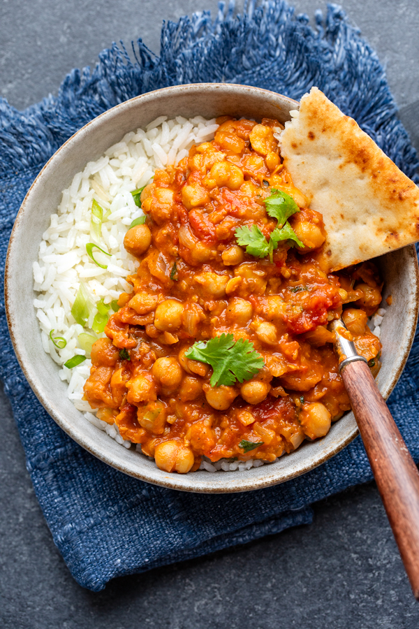 A bowl of Chana Masala with rice and naan | thecozyapron.com