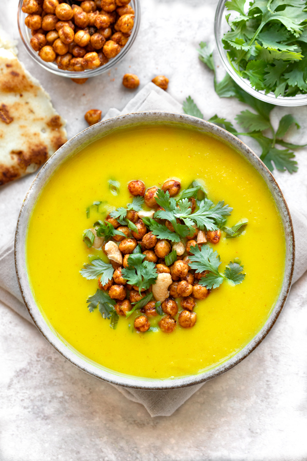 A bowl of Golden Soup topped with crunchy chickpeas and cilantro, and with a side of naan | thecozyapron.com
