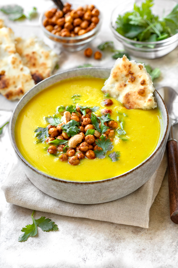 A bowl of Golden Soup topped with crunchy chickpeas and cilantro, and with a side of naan | thecozyapron.com