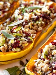 This fall-inspired stuffed delicata squash recipe is filled with ground turkey, sage, apples, wild rice blend, cranberries and pumpkin seeds! | thecozyapron.com #stuffeddelicatasquash #stuffeddelicatasquashrecipeturkey #stuffeddelicatasquashrecipewildrice #wildricestuffeddelicatasquash #delicatastuffedsquash #delicatasquashrecipe #delicatasquashrecipes