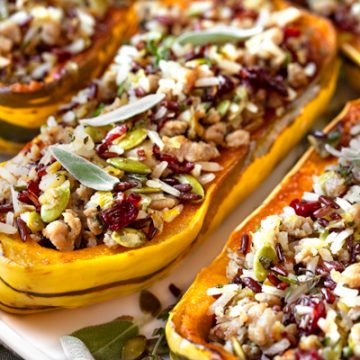 This fall-inspired stuffed delicata squash recipe is filled with ground turkey, sage, apples, wild rice blend, cranberries and pumpkin seeds! | thecozyapron.com #stuffeddelicatasquash #stuffeddelicatasquashrecipeturkey #stuffeddelicatasquashrecipewildrice #wildricestuffeddelicatasquash #delicatastuffedsquash #delicatasquashrecipe #delicatasquashrecipes