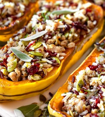 This fall-inspired stuffed delicata squash recipe is filled with ground turkey, sage, apples, wild rice blend, cranberries and pumpkin seeds! | thecozyapron.com #stuffeddelicatasquash #stuffeddelicatasquashrecipeturkey #stuffeddelicatasquashrecipewildrice #wildricestuffeddelicatasquash #delicatastuffedsquash #delicatasquashrecipe #delicatasquashrecipes