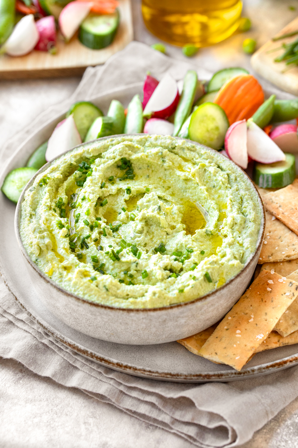 A large bowl of freshly made Edamame Hummus, served with crackers and veggies | thecozyapron.com