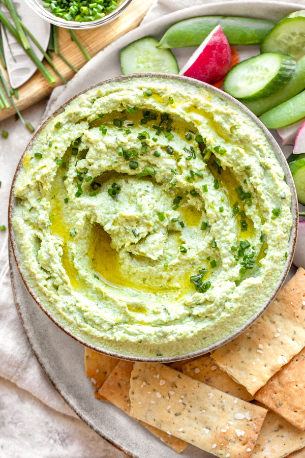 Overhead shot of a large bowl of freshly made Edamame Hummus, served with crackers and veggies | thecozyapron.com