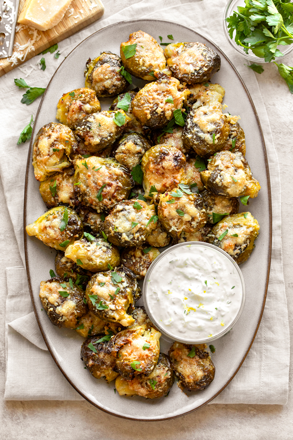 Overhead shot of Smashed Brussels Sprouts served on a platter, with Lemon Garlic Dipping Sauce | thecozyapron.com