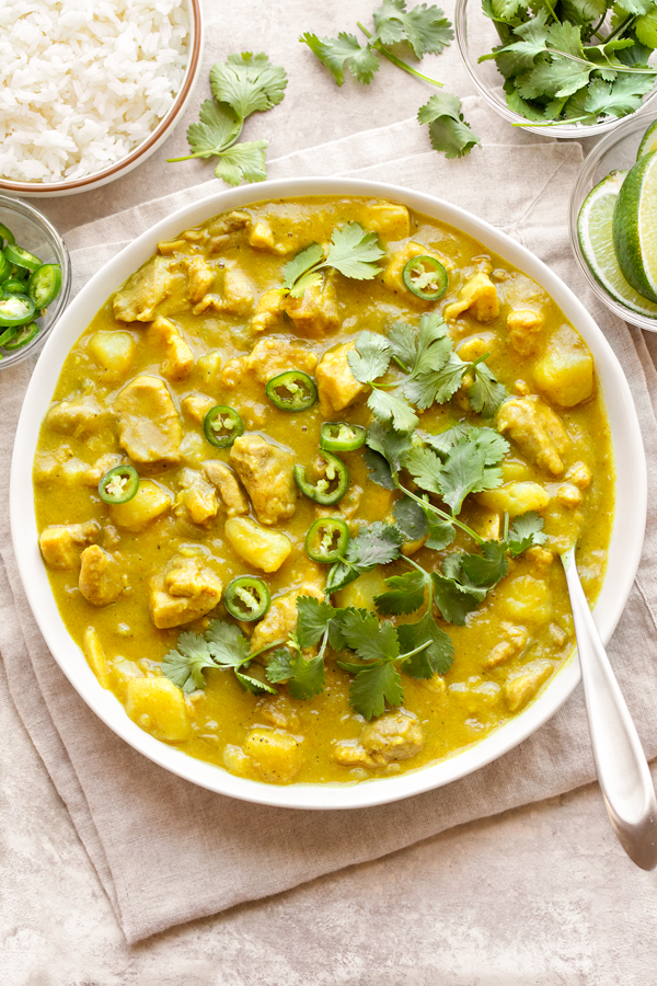 Overhead shot of a big bowl of Coconut Curry Chicken, with rice and add-ins on the side | thecozyapron.com