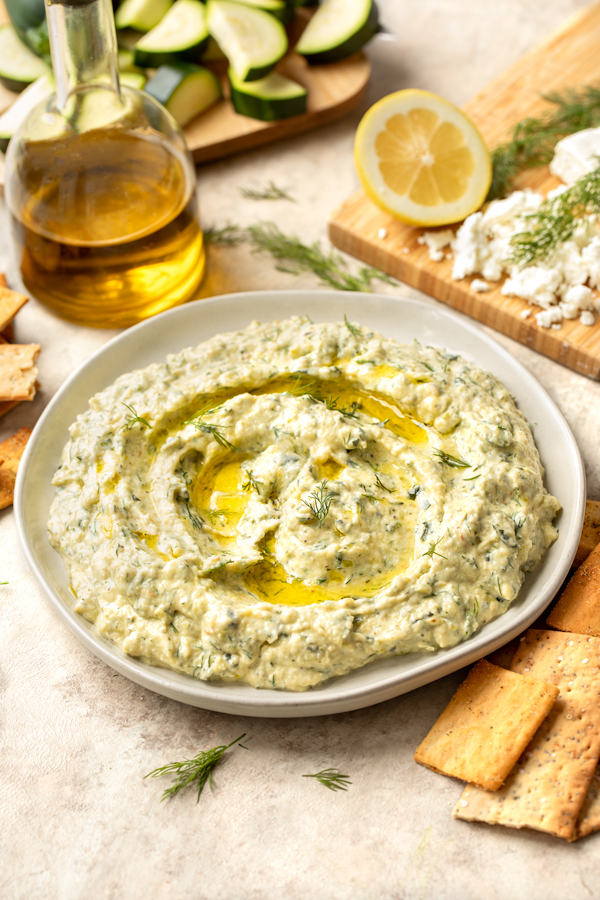 Roasted Zucchini Dip in a serving dish with crackers and olive oil on the side | thecozyapron.com