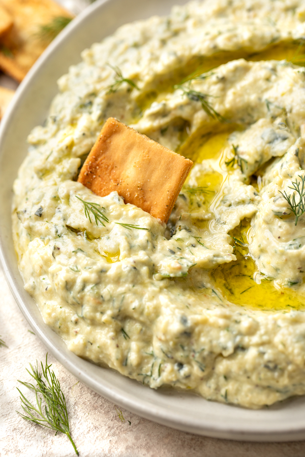 Closeup on a cracker dipped in Roasted Zucchini Dip | thecozyapron.com