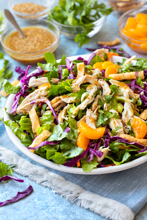 A big bowl of freshly made Chinese Chicken Salad with extra homemade sesame-ginger dressing and mandarin oranges on the side | thecozyapron.com