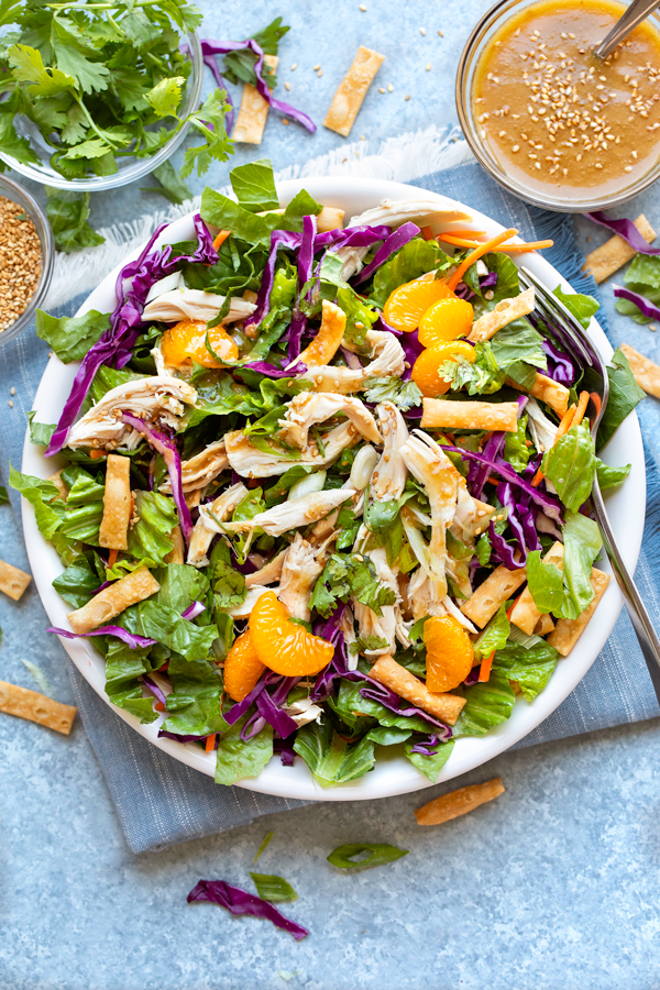 Overhead shot on a bowl of freshly made Chinese Chicken Salad with extra homemade sesame-ginger dressing and cilantro on the side | thecozyapron.com