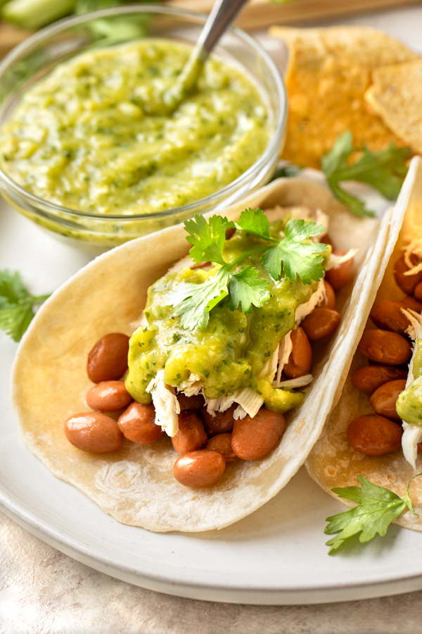 Fresh Salsa Verde drizzled over chicken tacos with pinto beans | thecozyapron.com