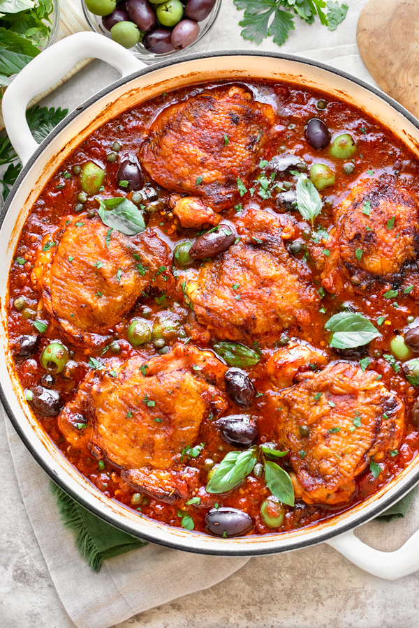 Overhead shot of homemade Chicken Puttanesca served in a cast iron braiser | thecozyapron.com