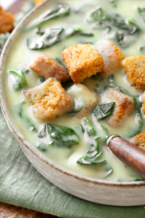 Closeup on a spoonful of homemade Spinach Soup topped with a couple crispy croutons | thecozyapron.com